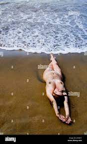 Nude sexy woman laying on Caribbean beach with waves around her and she is  covered with sand Stock Photo - Alamy