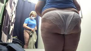 試着室のカメラは白いパンティーを履いた大きなお尻を見つめています。曲線美の熟女はパンツを試着します。ポーグ。アマチュアフェチ。