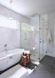 To add contrast, switch up your shower tiles. White Bathroom Free Standing Tub Monogrammed Towel Grey Floor Tile Glass Shower Transitional Bathroom Design Small Bathroom Remodel Small Master Bathroom