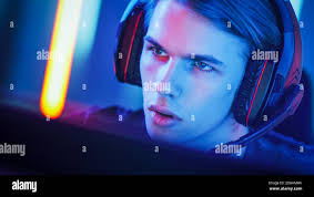 Portrait des Young Handsome Pro Gamer spielt in Online-Videospiel, spricht  mit Team-Spieler durch Mikrofon. Neonfarbenes Zimmer. E-Sport Cyber  Stockfotografie