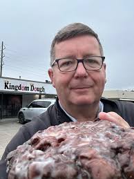 Cupcake Monster is sugaring up with a fritter from Kingdom Dough, LLC  before the Spirit of Christmas, Millbrook, Al parade.