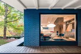 This stunning fireplace was constructed from reclaimed wood, adding a big dose of warmth and drama, while staying true to the rustic, shabby chic style of the room. In Situ Studio Revives Midcentury Modern Home In North Carolina