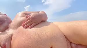 O velho homem de cabelos grisalhos gordo tem dia nu e cums na praia