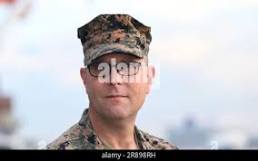 U.S. Marine Corps Col. Matthew J. Palma, the outgoing commanding officer of  Recruit Training Regiment (RTR), passes a microphone to Col. Joseph J.  Jones, the incoming commanding officer at Marine Corps Recruit