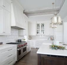 To create balance, complementing white polished ceramic tiles are used for the flooring while satin stainless steel appliances serve as subtle accents. Painted White Kitchen With Dark Wood Island Crystal Cabinets