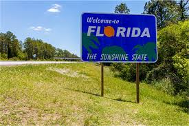 It reads welcome to florida / the sunshine state in white text on a dark blue background. Domicile In Florida Durfee Law Group
