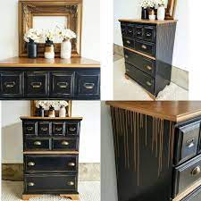 Green tall boy dresser with vintage hardware and detailed trim in a transitional bedroom beside a black and white chair accented. Lamp Black And Gold Drip Dresser Gold Furniture Black Painted Furniture Gold Painted Furniture