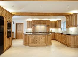 A modern style orange kitchen, with a sleek breakfast island, bar type stools, and tiled floors. Traditional Kitchens Charnwood Kitchens