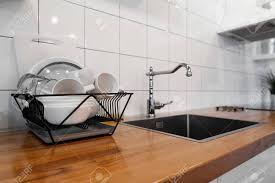 Suitable for use with a food waste disposer. Budget And Lightweight Antimicrobial Dish Drainer With Drain Board At Modern Scandinavian Kitchen Dish Rack Holds Many Dishes And Cups Against Wooden Countertop White Wall Tiles Sink And Faucet Stock Photo Picture