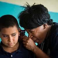 Cmdr. Kerry Ebueng examines a patient at a medical site established at  Centro de Educacion Basica Dr. Jesus Aquilar Paz