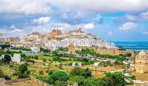 From the red earth grow silvery olive trees crowned with green, while the while city stretches before you under an azure sky. Ostuni Apulien Italien De