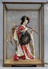 The geisha dolls have an exaggerated elegant. Sold Price Vintage 1950 S Japanese Geisha Doll In Full Kimona Dress And Carrying A Parasol And A Branch With Leaves Doll Set In A Wood And Gla January 5 0119 10 00 Am Cst