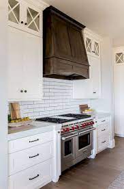 Glass fronted cabinets, wooden parts of the range hood and the white stone countertop have natural and nice look together. Wood Kitchen Cabinets An Investment To Awesome Kitchen Home To Z New Kitchen Cabinets Kitchen Design Kitchen Remodel