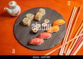 Assorted Sushi On A Circular Black Slate Plate And Sauce Boat With Soy Sauce Salmon Makis Tuna And Salmon Nigiri Uramaki With Sesame Seeds And Avoc Stock Photo Alamy