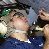 Aviation Structural Mechanic 3-го класса Brandon Haag вручает Mate  авиационного машиниста 2-го класса Николаса Гарднера панель крыла во время  проведения ремонтных работ на P-3C Orion.