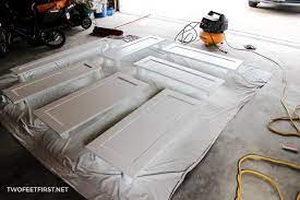 Spraying the first coat of finish on the cabinet door. How To Paint Kitchen Cabinets With A Sprayer