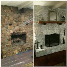 A whitewashed brick fireplace with a wooden mantel, rustic decor and potted greenery is rustic and cozy. White Wash Rock Fireplace 50 White Primer 50 Water Brush On And Dab With A Wash Cloth Stone Fireplace Makeover Rock Fireplaces Fireplace Remodel