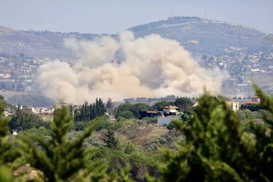 Smoke rises over a residential area in southern Lebanon following an Israeli airstrike, with emergency vehicles visible nearby.