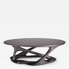 This coffee table has a simple oval shape, tempered glass top, and four straight legs that create clean lines. Amorph Amorph Tetra Table Oval Shape With Organic Design Dark Gray Metallic Finish