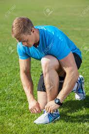 Cheerful Man Is Kneeing And Tying His Shoelaces On Grass. He Is Looking At  It With Attention Stock Photo, Picture And Royalty Free Image. Image  42671012.