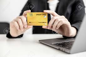 Using a credit card to make a car loan payment could mean you pay two types of interest charges. A Business Woman Holds A Credit Card To Make Payments On The Website Where She Is