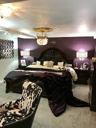 A vintage glam bedroom with a crystal chandelier, a mirror, printed textilesand lamps and candles. Plum Silver Gold Ivory Black Master Bedroom Black Master Bedroom Purple Master Bedroom Purple Bedrooms