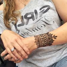 Cuff Like Small Henna Tattoo In Dark Brown With Leaf Motifs And Flourishes Decorating The Arm Of A In 2020 Henna Tattoo Wrist Henna Designs Wrist Henna Tattoo Designs
