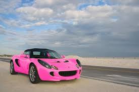 People riding on pink convertible coupe parked near white concrete. Pink Lotus Elise Sports Car Wallpaper Lotus Elise Car Wallpapers