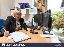a business administrator office manager by her desk in a busy office Stock Photo - Alamy
