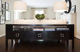 Four doors with angled edges open to reveal two cabinets with a shelf in each. Sofa Table Transitional Living Room Jennifer Worts Design Console Table Behind Sofa Transitional Living Rooms Elegant Living Room