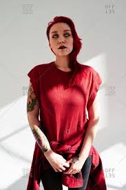 Snow white with the red hair. Portrait Of Young Woman With Dyed Red Hair Piercing And Light Blue Eye Contact Lens Standing On White Wall Background Her Hand Covered With Colorful Tattoos Stock Images Page Everypixel