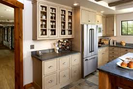 Rustic knotty alder with stain and glaze finish by shaw cabinetry & woodworks, half moon bay custom kitchen, includes knotty alder cabinets, porcelain tile backsplash and floors, azul slab the island and desk area are signature blackstone stain with black highlight, distressing and cracking. See This Antique Persona Kitchen Showplace Cabinetry