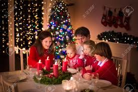 Big Family With Three Children Celebrating Christmas At Home Festive Dinner At Fireplace And Xmas Tree Parent And Kids Eating At Fire Place In Decorated Room Child Lighting Advent Wreath Candle Stock