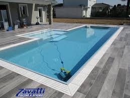 Vista Totale Piscina A Sfioro Con Griglia In Pietra Bianca A Quattro Fessure E Rivestimento Grigio Chiaro Design In Armonia Con La Pavimentazione Che Circonda La Piscina Zavatti Piscine
