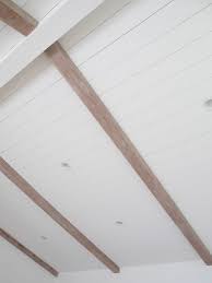 This rustic living space has multi colored tile flooring and large logs cut in half used for the exposed beam look on the ceiling. Vaulted Ceiling White Shiplap Ceiling Paneling Master Suite Renovation Shiplap Ceiling Painted Wood Ceiling Vaulted Ceiling Living Room
