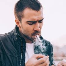Adolescent Vapoteur. Beau Jeune Homme Blanc Barbu En Casquette Noire Fumant  Une Cigarette Électronique En Face Du Fond Marron Moderne En Automne.  Banque D'Images et Photos Libres De Droits. Image 108148522