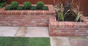 Turn a pile of leftover bricks into a stylish planter you can use for years to this brick planter sits against a lovely stone house beside two other planters. Brick Planters Do Around The Patio In The Back Yard Brick Planter Brick Garden Brick Garden Edging