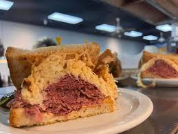 Image of Stateside Deli Reuben sandwich with corned beef, Swiss cheese, and sauerkraut on grilled rye bread