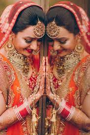 Groom giving bride's mother a coconut. Bride Portraits Gold Jewelry Choker And Maang Tikaa With An Orange And Red Lehe Indian Wedding Photography Poses Wedding Photography Poses Bridal Photoshoot