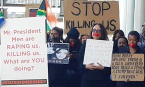 A group of people holding a sign: Policeman Friend Beaten Up After Cape Town Woman Allegedly Raped News24