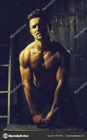 性感性感肌肉时尚年轻的帅哥裸照裸露躯干与美丽的身体站在台阶与硬大复古手提箱室内木制背景垂直的图片—  图库照片©Tverdohlib.com＃180157882