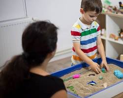 therapist playing with a child using sand tray therapy resmi