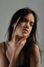 Reconsidering. Beautiful earnest long-haired young woman thinking and  looking down and wearing a top