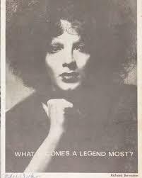 A poster featuring Jackie Curtis Pictured: A black and white poster with a  headshot of Jackie Curtis looking directly at the camera. “What Becomes A  Legend Most?” is printed toward the bottom