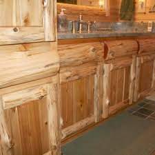A wall of knotty pine pantry cabinets brings rustic charm and a golden glow to this kitchen, where a lack of ceiling exposes joists as rugged companions. Cabinetry Kitchens And Baths Timber Country Cabinetry