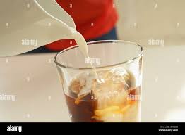 Milk Pouring Into Glass Of Iced Coffee Close Up Stock Photo Alamy