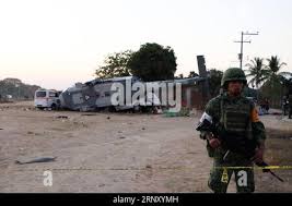 A Mexican soldier stands guard in front of a charred auto in front of the  Piedras Negras City Hall and jail, Dec. 31, 1984, after supporters of a  defeated mayoral candidate set