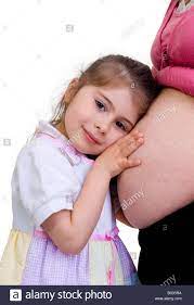 A Young Girl Listens To Her New Baby Siter In Her Mommy S Tummy Stock Photo Alamy
