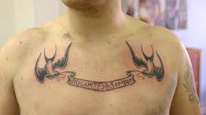 The design shows a red heart outlined in black ink, with a pair of silver wings. Top 10 Scroll Tattoo Designs