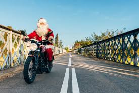 Santa claus riding down the highway on a motorcycle, no not with a sleigh and reindeers a motorcycle. Santa Claus Riding A Motorcycle On The Road Indivstock